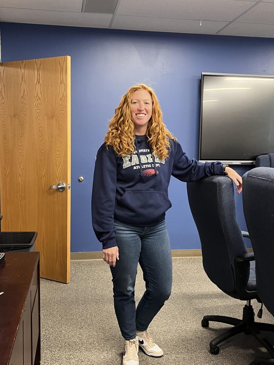 Rachel Parker poses in the Eagle conference room, wearing a Dakota Ridge branded shirt that ironically states, “Property of Eagles Athletic Department.” 