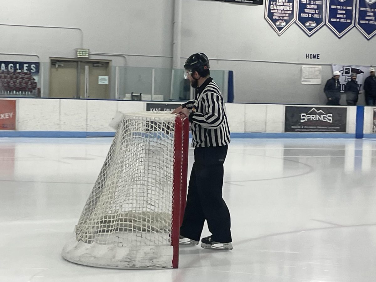 The hockey referees begin to set the goals back up and prepair for the second period of the game.